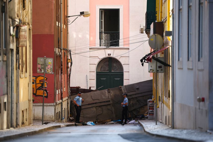 Police officers are standing near the site of the accident the day after a Gloria sexual railway car derailed and crashed in Lisbon, Portugal.