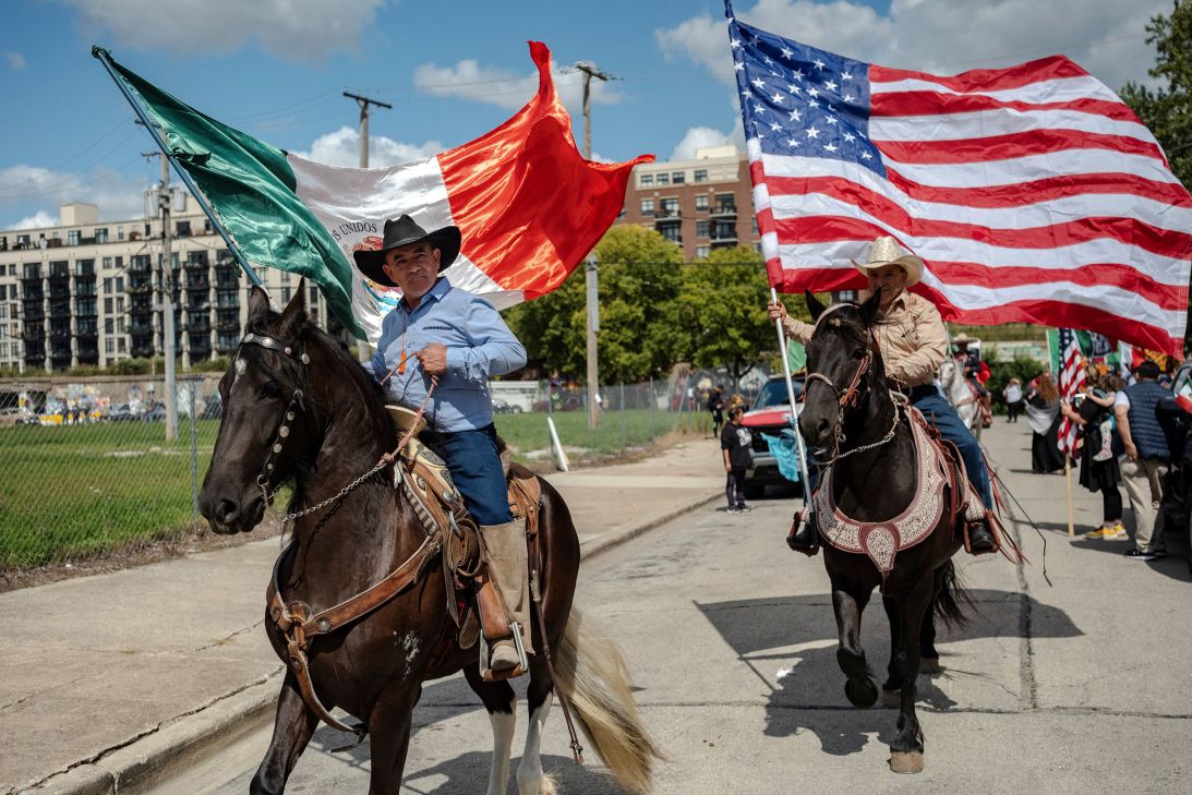 Parade participants on horseback carry the Mexican and American flags during a Mexican Independence Day celebration in Chicago.
