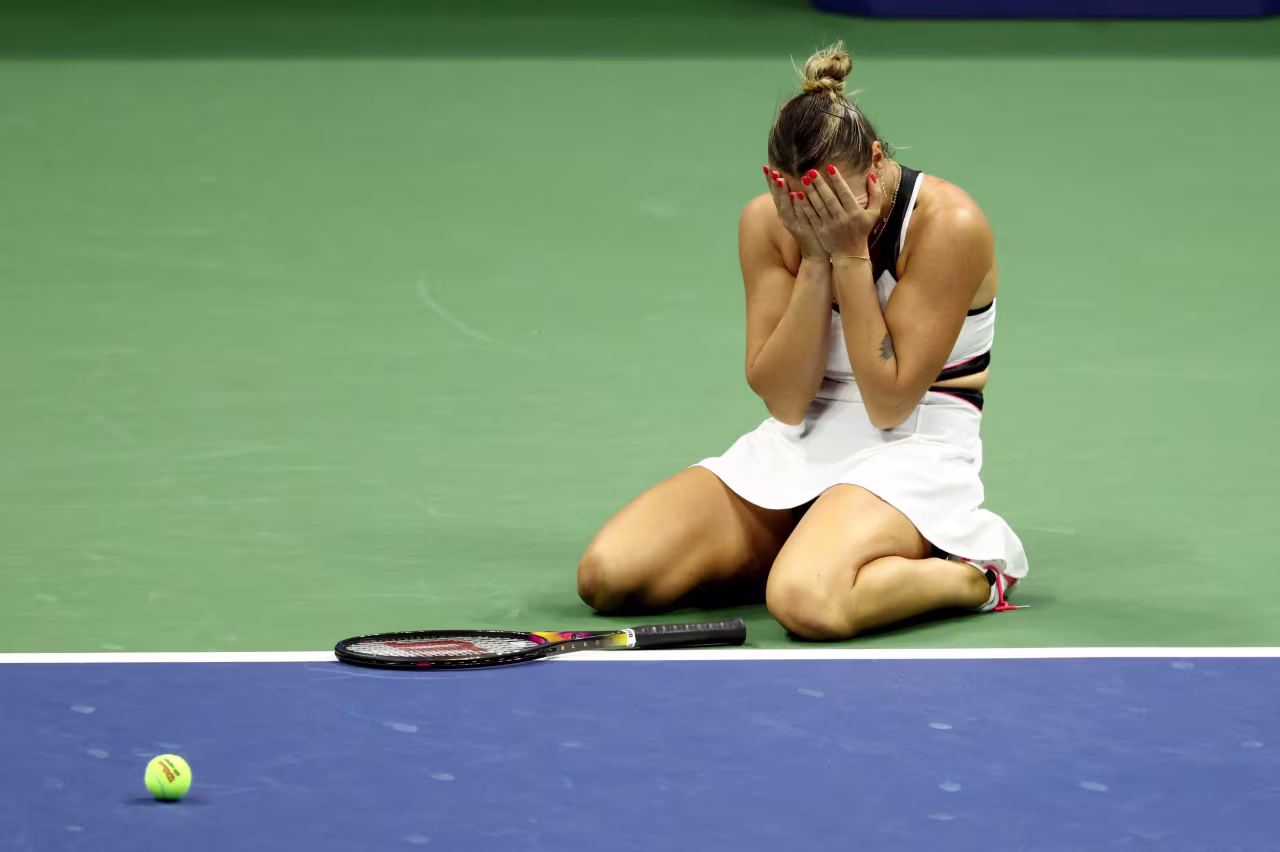 Aryna Sabalenka falls to her knees after winning match point.