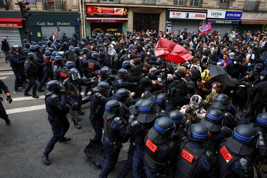 Police officers in riot gear clash with demonstrators gathering in Paris.