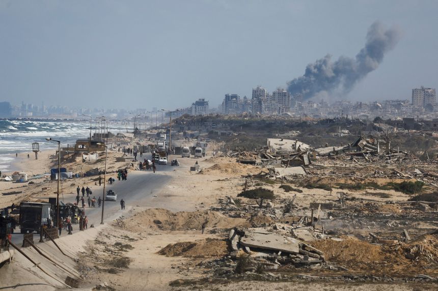 Smoke rises from an Israeli strike, as displaced Palestinians fleeing northern Gaza move southward after Israeli forces ordered residents of Gaza City to evacuate to the south, in central Gaza, on September 25.