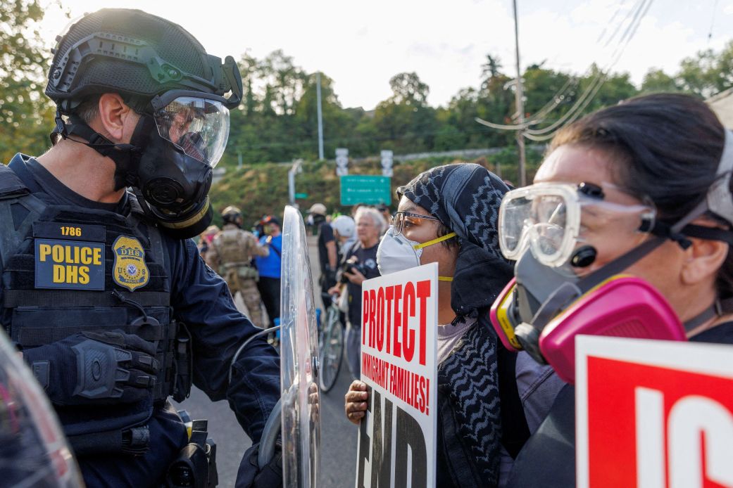 A federal officer stands guard in front of demonstrators as they protest against Immigration and Customs Enforcement in Portland, Oregon, on Sunday, September 28.