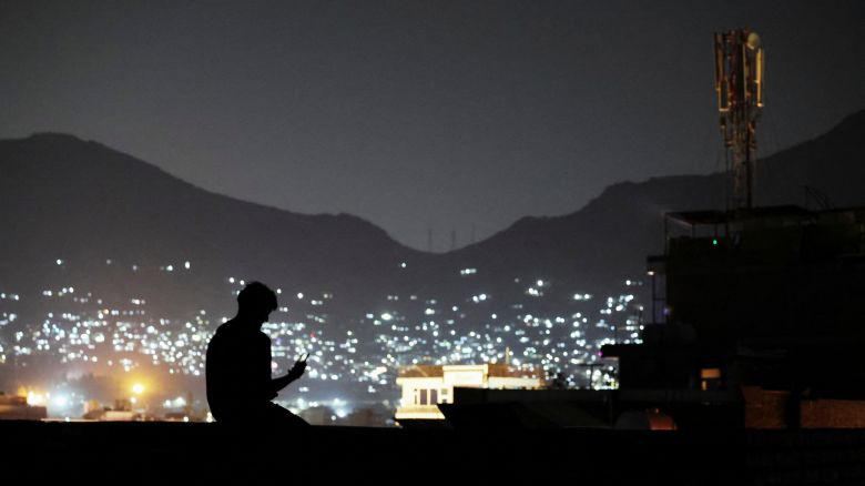 A man sits on a wall while talking to someone on a video call, after telecom and internet services resumed in Kabul, Afghanistan, on October 1, 2025.