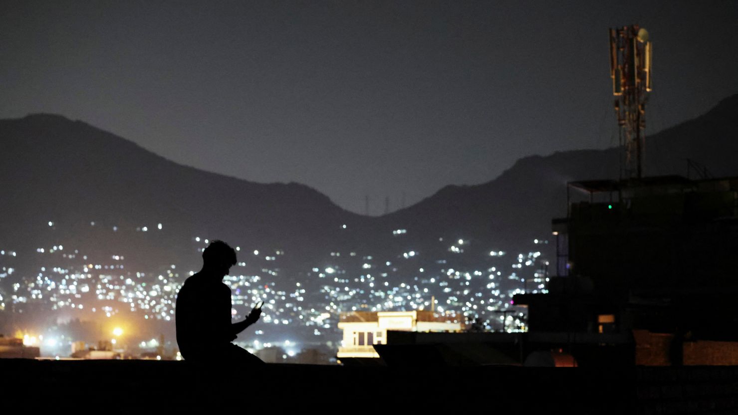 A man sits on a wall while talking to someone on a video call, after telecom and internet services resumed in Kabul, Afghanistan, on October 1, 2025.