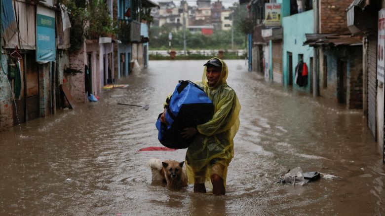A man carries a bag as he wades through a flooded street along the bank of overflowing Bagmati River following heavy rains, in Kathmandu, Nepal, October 4, 2025. REUTERS/Navesh Chitrakar