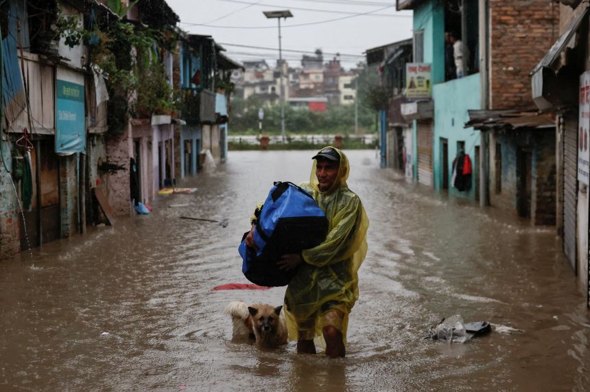 A man carries a bag as he wades through a flooded street along the bank of overflowing Bagmati River following heavy rains, in Kathmandu, Nepal yesterday.