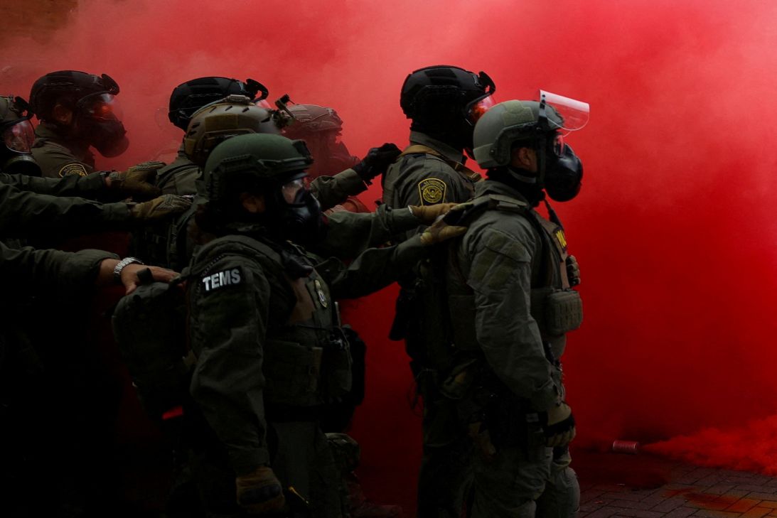 Policiais ficam em meio à fumaça após uma granada de fumaça ser lançada para dispersar manifestantes em frente à sede do ICE em Portland, Oregon, em 4 de outubro.