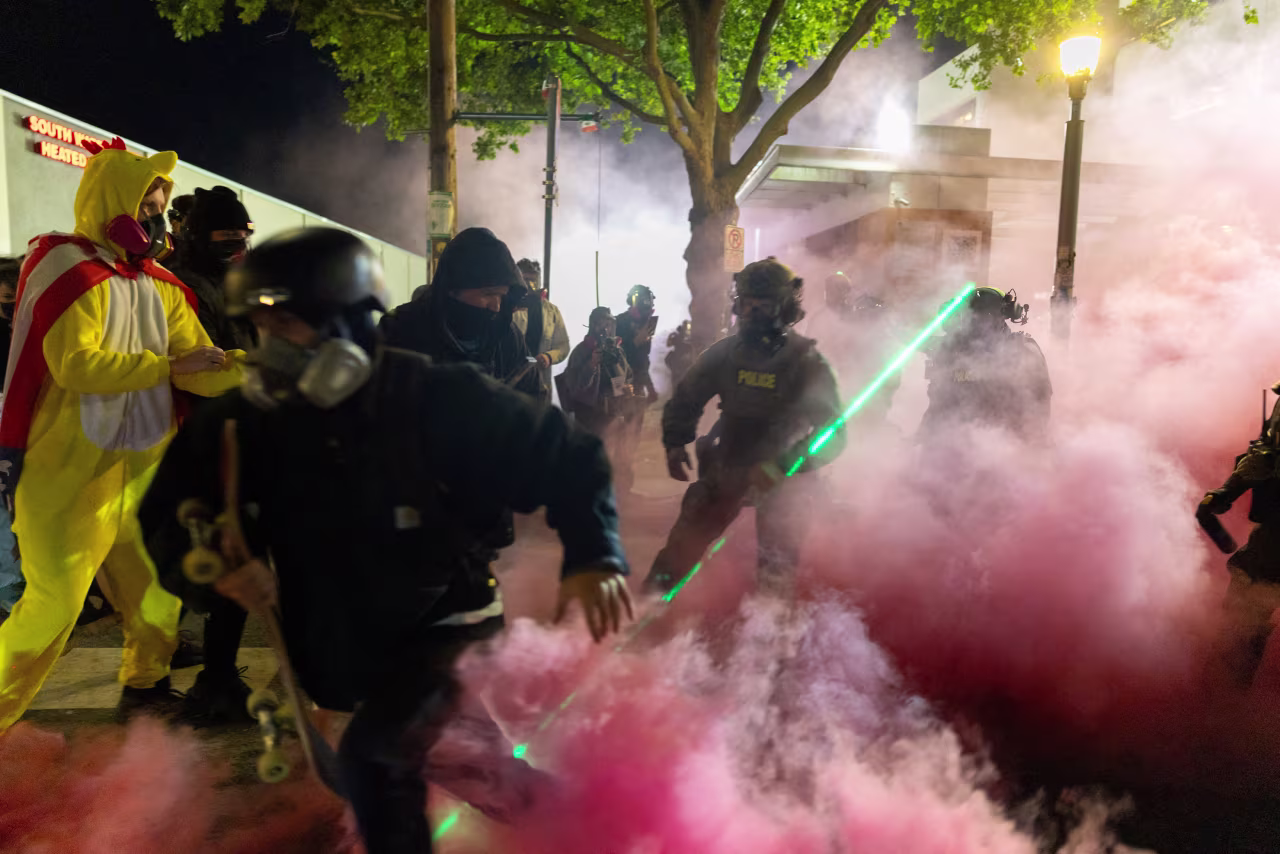 A protestor reacts as law enforcement officers deploy smoke grenades to disperse people gathered outside the Immigration and Customs Enforcement headquarters in Portland, Oregon, on Sunday.