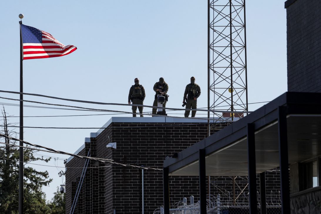 US Border Patrol officers look at protesters from the rooftop of the ICE Broadview facility in Chicago, Illinois, on Thursday.