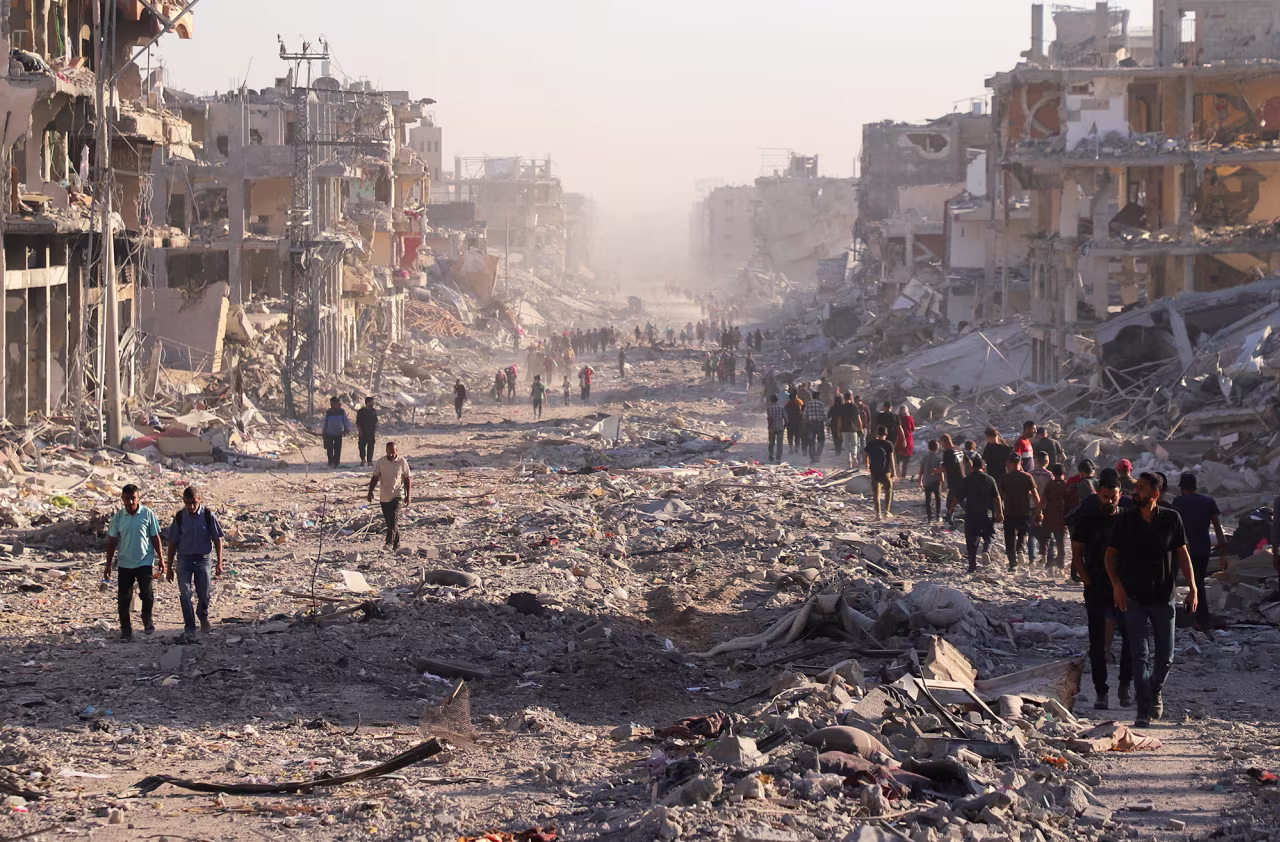 Palestinians walk through a damaged neighborhood in Gaza City on Friday.