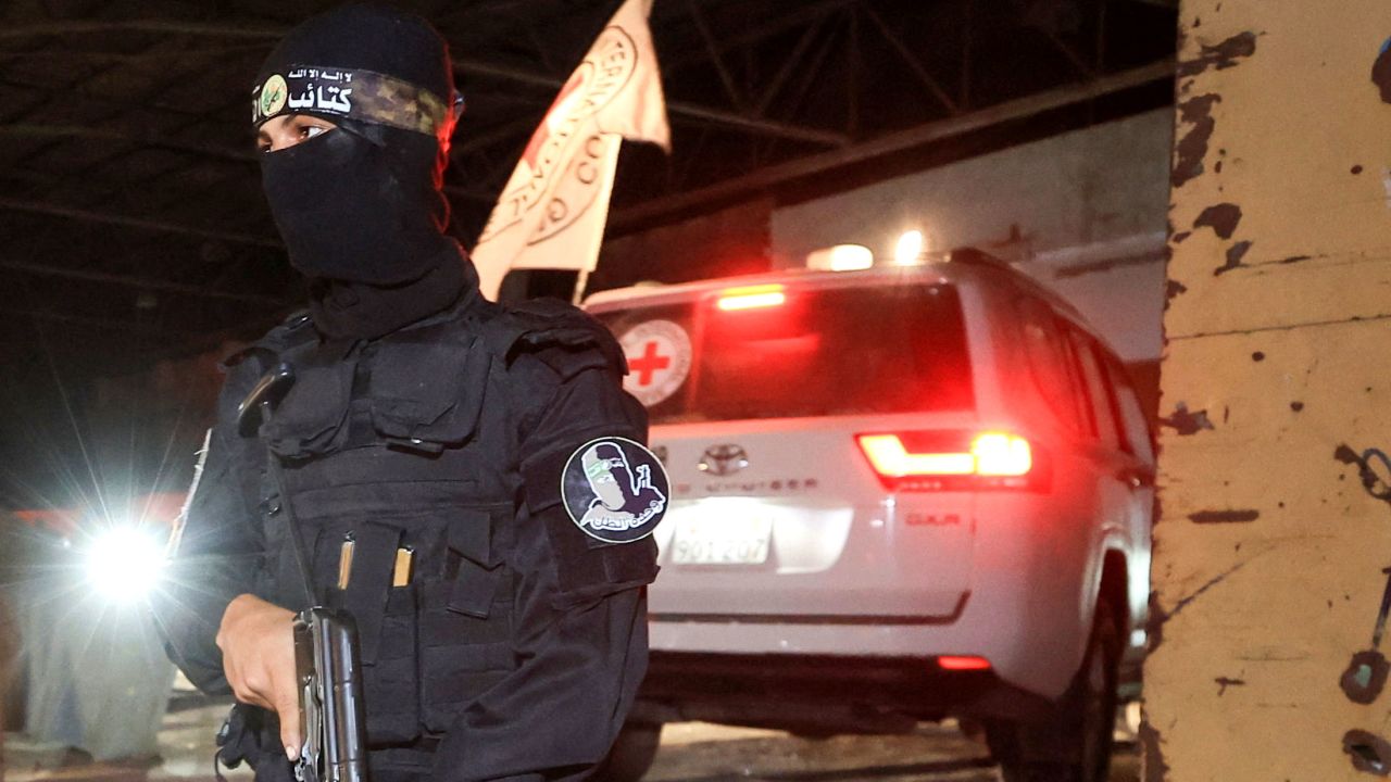 An armed Hamas militant stands guard as a Red Cross vehicle arrives to receive the bodies of deceased Israeli hostages, in Gaza City, on Tuesday.