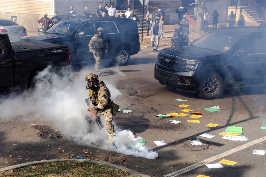 A federal agent prepares to throw a tear gas canister at community members in Chicago on Tuesday.