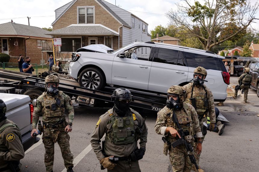 Federal agents stand guard in front of a wrecked vehicle used by agents during a chase to detain a man on Chicago’s South Side on October 14.