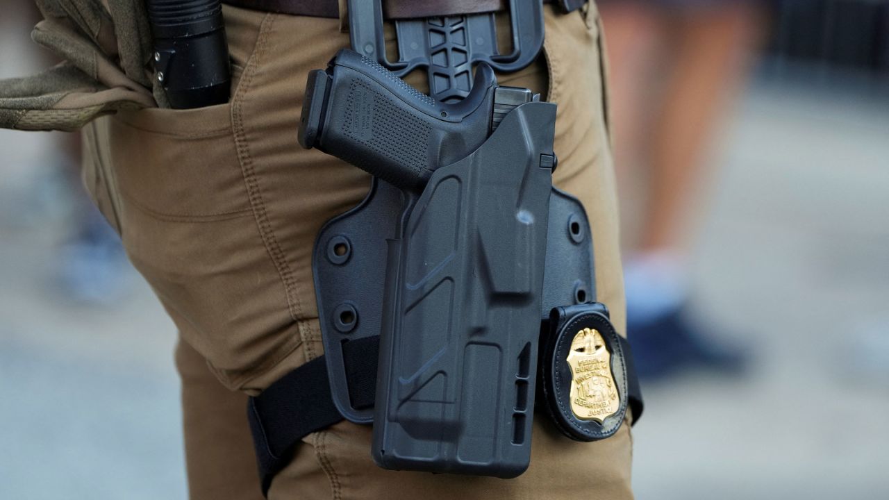 The gun and badge of an FBI agent as he stands in the entertainment district Beale Street, in downtown Memphis, Tennessee, on October 16, 2025.