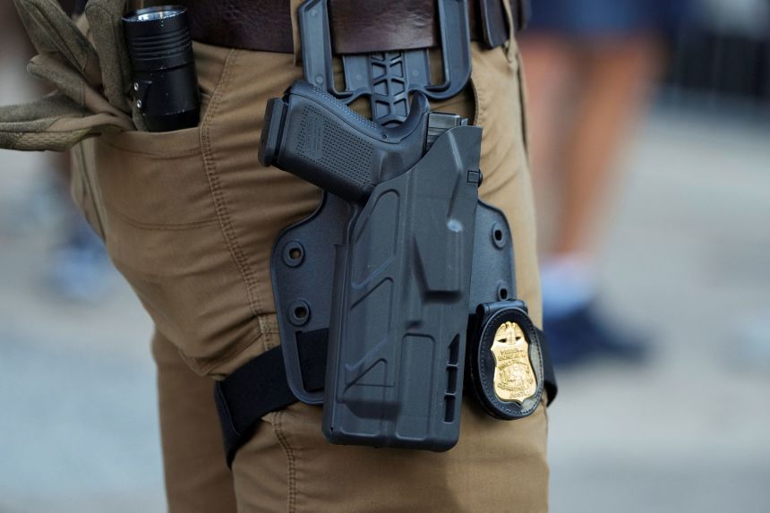 The gun and badge of an FBI agent as he stands in the entertainment district Beale Street, in downtown Memphis, Tennessee, on October 16, 2025.