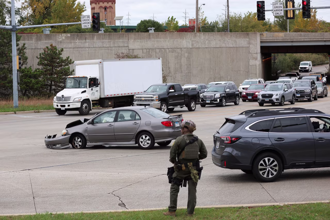A federal agent stands guard after a crash between two civilian vehicles at an intersection in the Cicero neighborhood during an immigration raid in Chicago, Illinois, on Wednesday.