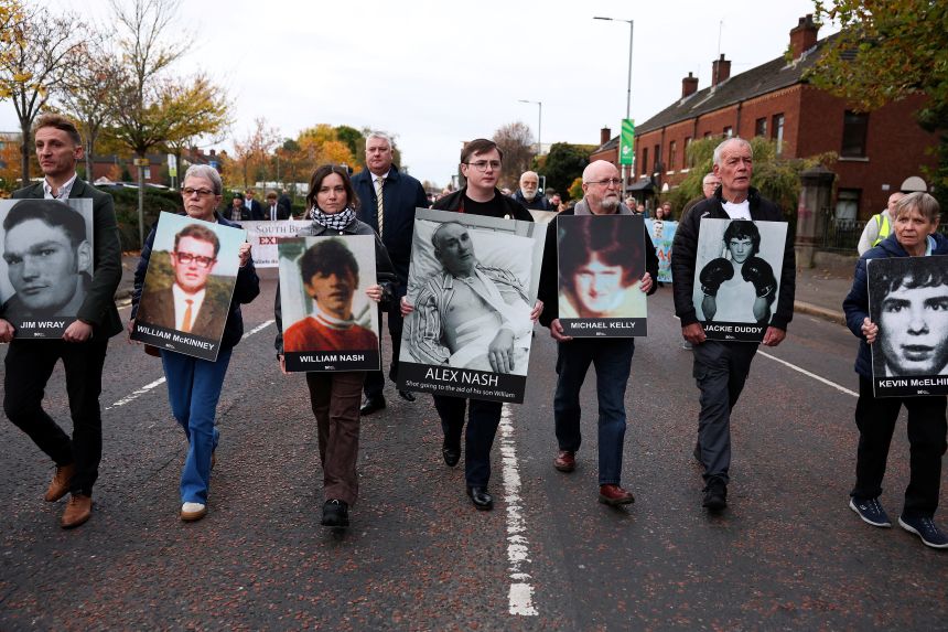Family members hold pictures of victims of the 1972 "Bloody Sunday" killings as the murder trial takes place in Belfast, Northern Ireland, on October 23, 2025.