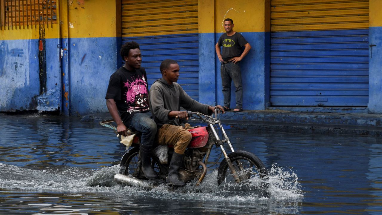 People transit on a motorcycle through a street flooded by rains caused by Tropical Storm Melissa, in Santo Domingo, Dominican Republic, October 23, 2025. REUTERS/Eddy Vittini