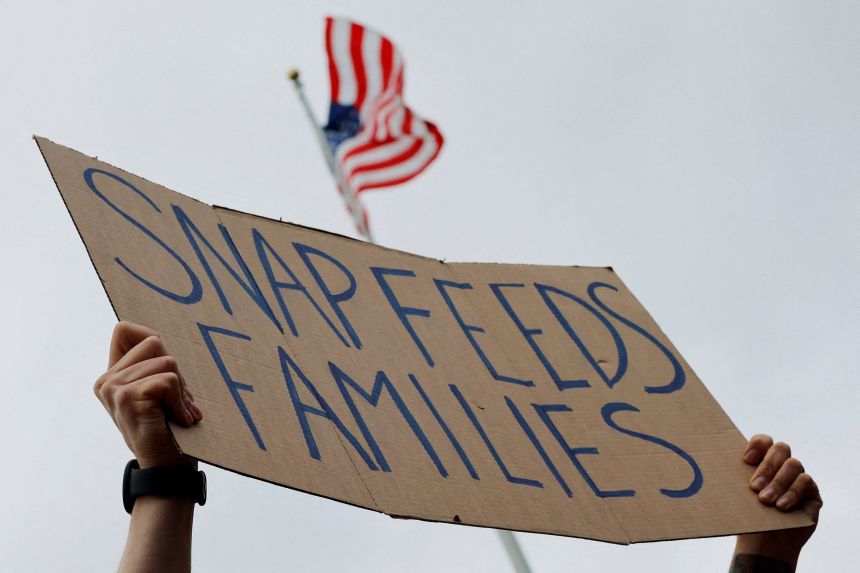 A man holds a sign reading "SNAP Feeds Families" during "A Rally for SNAP" on the steps of the Massachusetts State House in Boston on Tuesday.