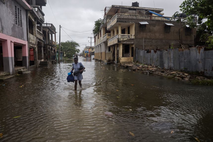 A woman holds onto her belongings after heavy rains flooded parts of Les Cayes, Haiti, on Wednesday.
