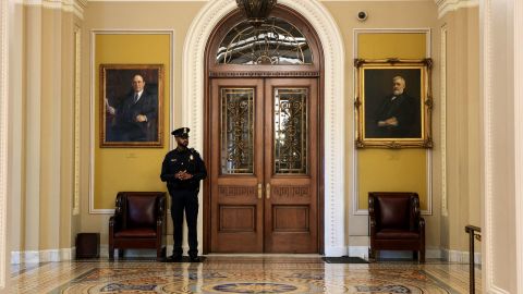 A US Capitol Police officer stands guard in the empty hallway outside the darkened Senate Floor on Friday.
