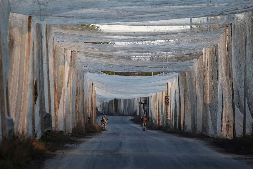 Ukrainian servicemen walk along a road covered with anti-drone nets in the frontline town of Kostiantynivka, in Ukraine's Donetsk region, on November 3.