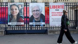 A woman walks past posters with the portraits of Cecile Kohler and Jacques Paris, two French citizens held in Iran, in Paris on May 7.