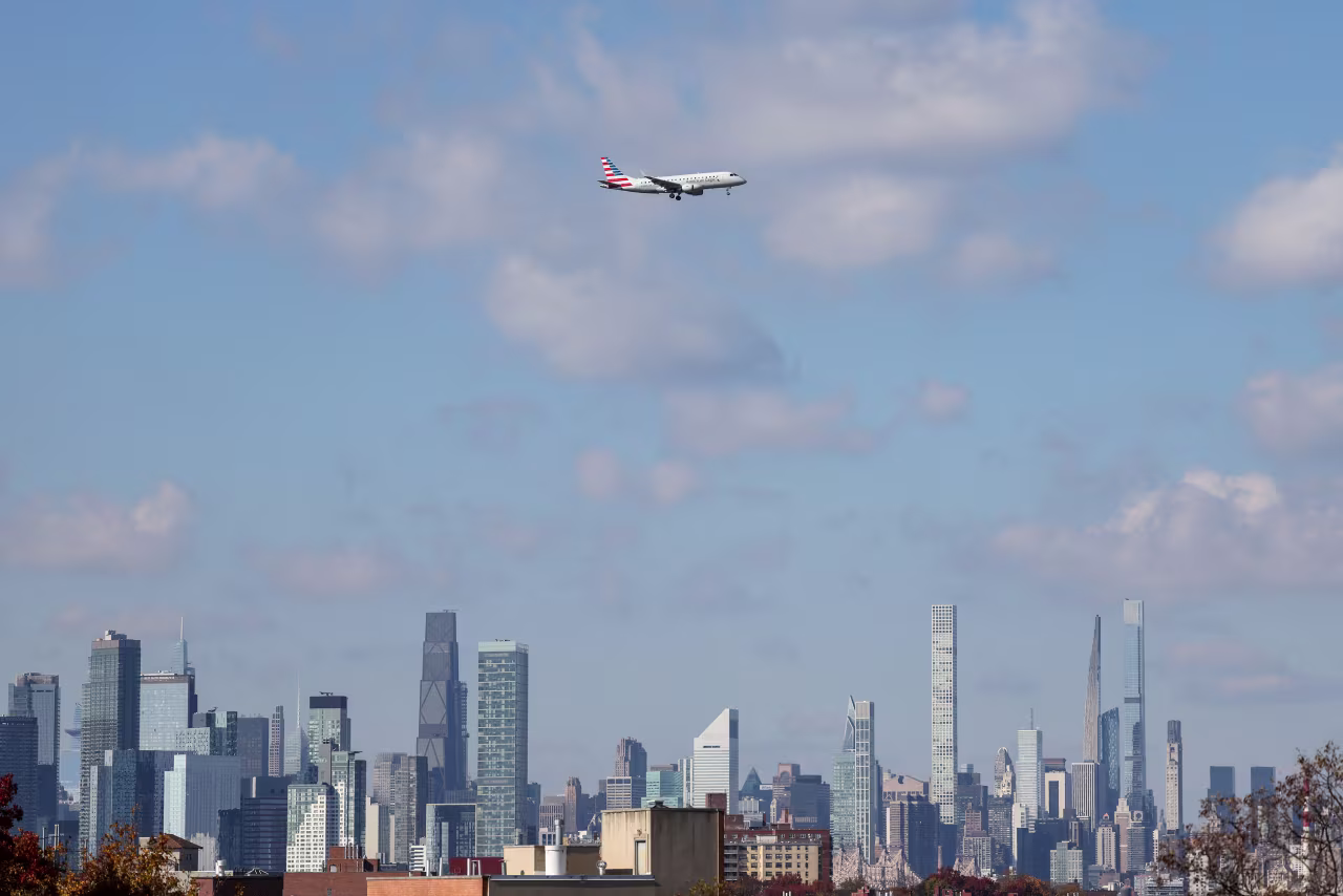 An American Eagle plane flies near the Manhattan skyline as it lands at LaGuardia Airport on November 8, 2025.