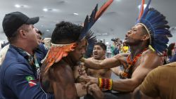 An Indigenous demonstrator is held by a staff member as protesters force their way into the venue hosting the UN Climate Change Conference (COP30), in Belem, Brazil, on November 11, 2025.
