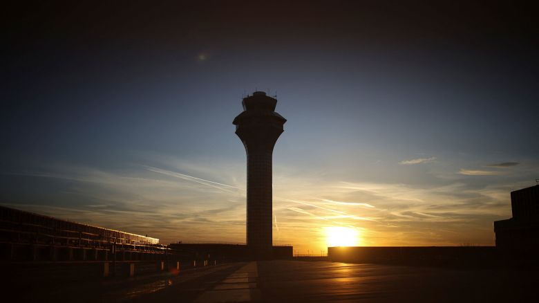 The sun sets over an air traffic control tower at O'Hare International Airport in Chicago. A shortage of air traffic controllers became worse due to resignations and retirements during the recent government shutdown.
