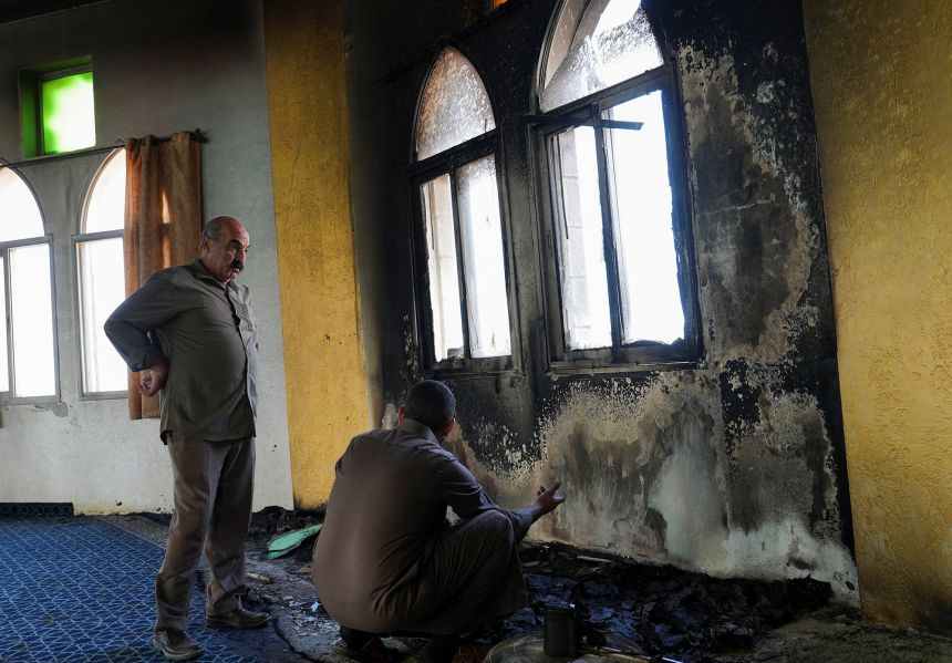 A Palestinian man inspects burnt items inside a mosque.