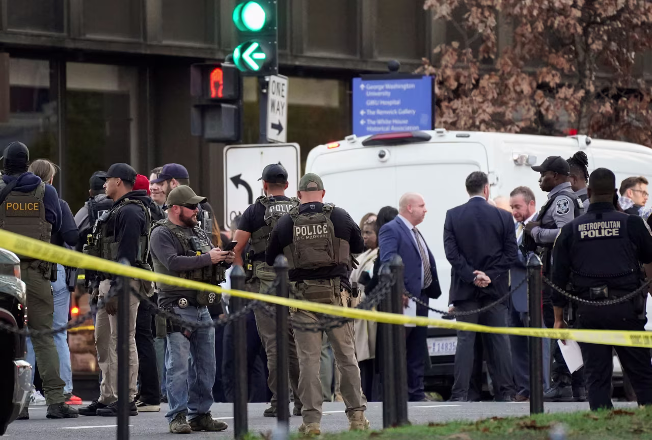 Law enforcement officers stand behind yellow tape, after two National Guard members were shot near the White House on Wednesday.
