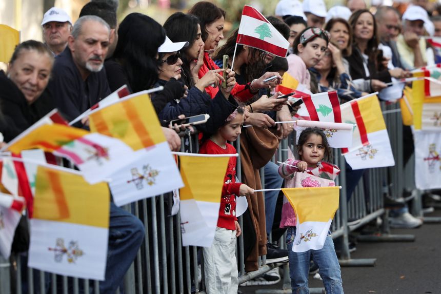 People holding Lebanese and Vatican flags gather in Baabda, Lebanon, on Sunday, awaiting the arrival of Pope Leo.