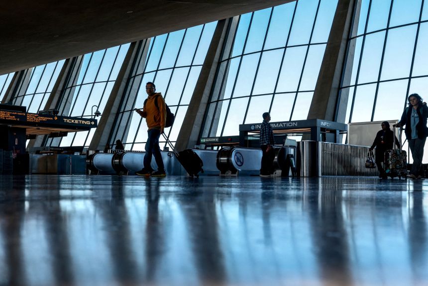 Travelers walk through Dulles International airport in Dulles, Virginia, on November 13, 2025.