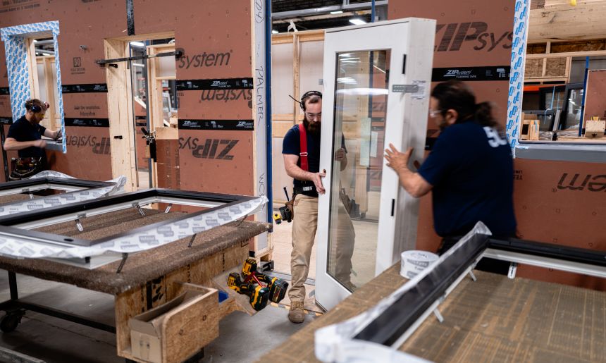Workers install windows and doors in one Unity home panel.