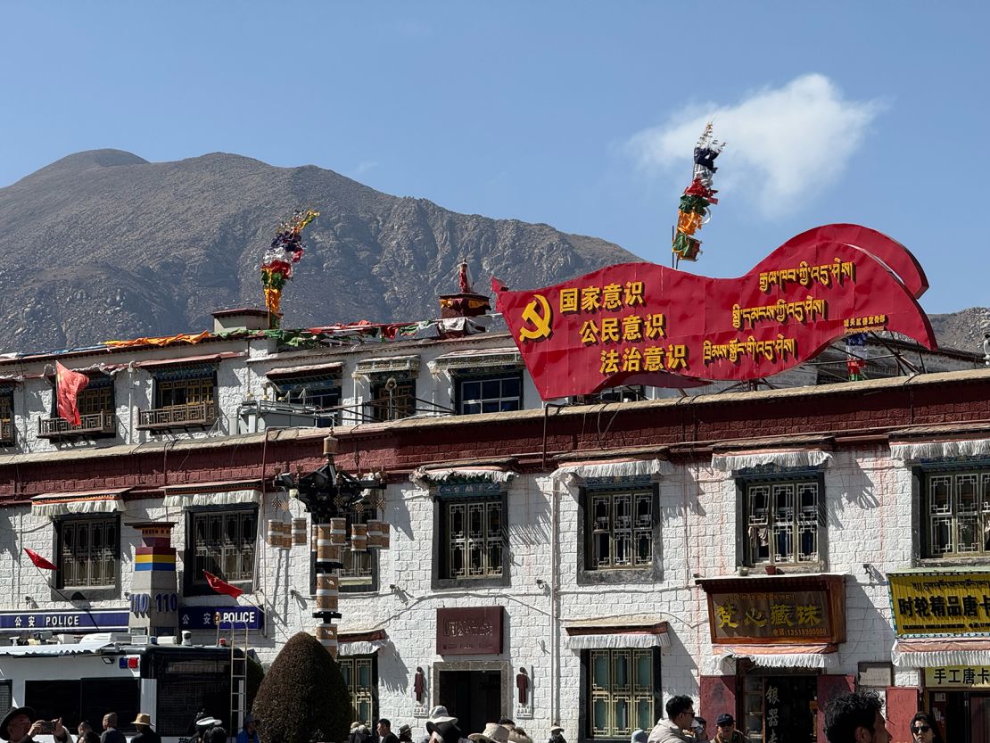 A banner promoting patriotic education on the bustling Barkhor Street in Lhasa, where shops stand next to a police station.