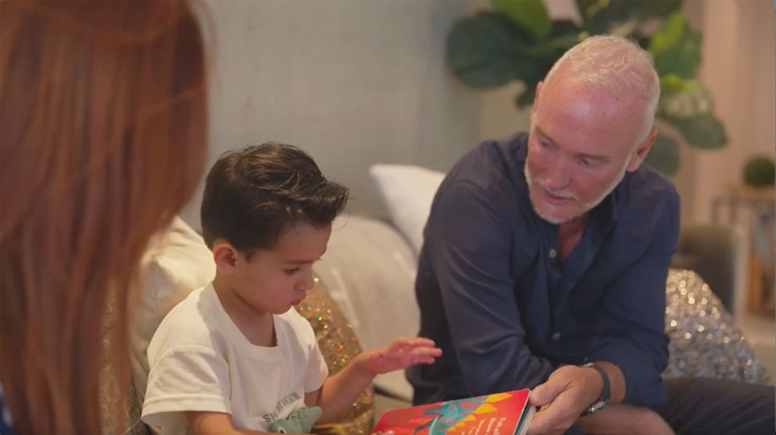 Simon Nicholls reads with his 3-year-old son, Sylver, at his home in Miami.