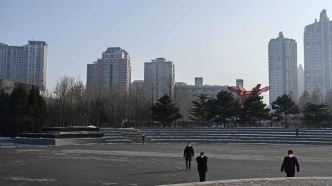 People wear protective masks as they walk in a nearly empty Chaoyang Park in Beijing on Sunday.