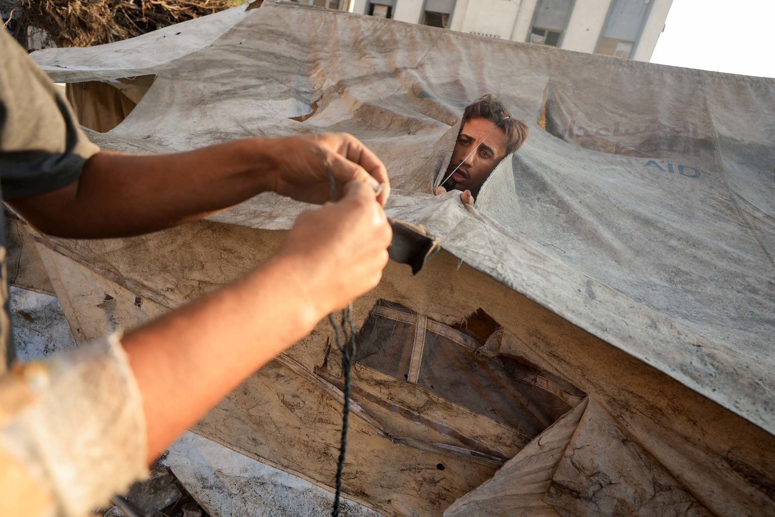 Palestinians in Gaza City repair their tent, which had been damaged in an overnight Israeli airstrike, on Saturday, September 13.