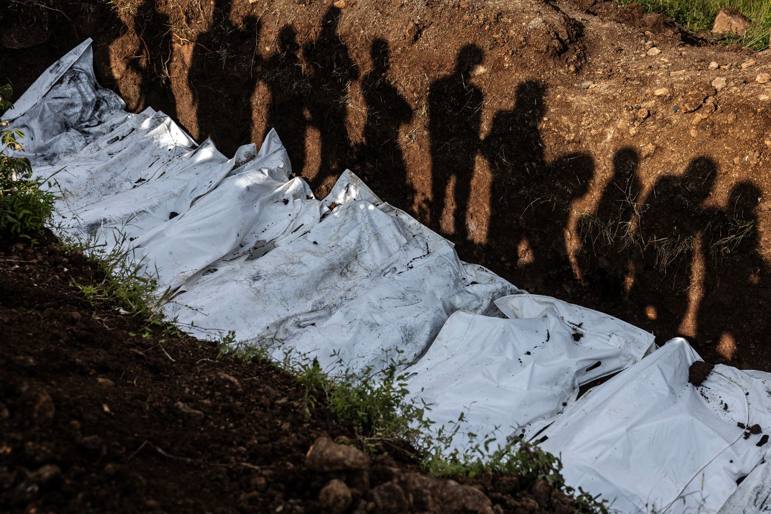 Local residents’ shadows are seen as they watch members of the Congolese Red Cross conduct a mass burial for people in Bukavu, Democratic Republic of Congo, on Thursday, February 20. <a href="https://www.cnn.com/2025/02/15/africa/drc-rebels-advance-on-bukavu-intl/index.html">Clashes between Congolese forces and a rebel group</a> have left thousands dead, according to the DRC’s government.