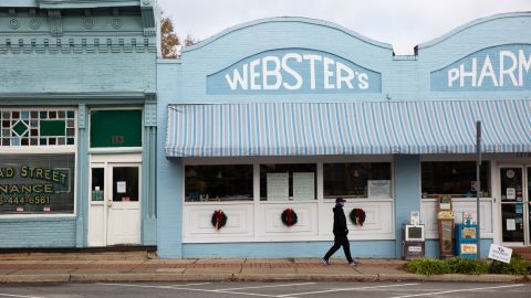 A person walks past a downtown Sparta pharmacy. A sign in its window urges residents to buy locally.