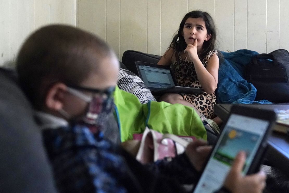 Third grader Elena recites multiplication tables as her brother Wyatt reviews his kindergarten work on a tablet with their mom, Christi Brouder, in Haverhill, Massachusetts. 