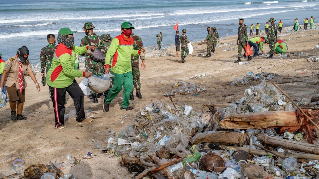 Workers clean up piles of debris and plastic waste brought in by strong waves at Kuta Beach in Bali, Indonesia, on January 1, 2021.