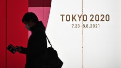 A man walks along a corridor past an official Tokyo 2020 Summer Olympics advertisement board in the Shinjuku district of Tokyo on November 30, 2020. (Photo by Philip FONG / AFP) (Photo by PHILIP FONG/AFP via Getty Images)