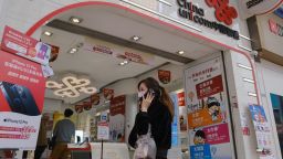 A pedestrian wearing a protective mask walks past signage at a China Unicom Hong Kong Ltd. store in Hong Kong, China, on Monday, Jan. 4, 2021. China's state-owned telecommunications companies declined in Hong Kong after the New York Stock Exchange said it's delisting them to comply with a U.S. executive order that sanctioned companies identified as affiliated with the Chinese military. Photographer: Roy Liu/Bloomberg via Getty Images