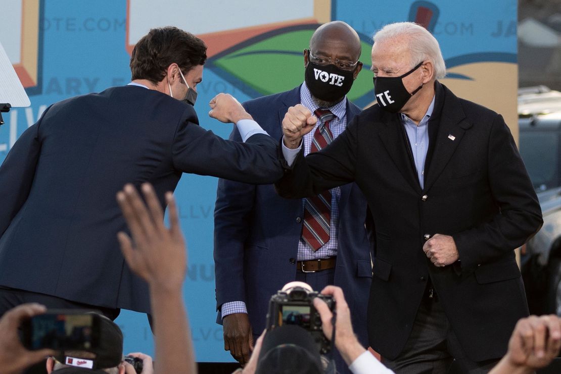 Democratic candidates for Senate Jon Ossoff, left, and Raphael Warnock bump elbows with US President-elect Joe Biden during a rally  in Atlanta on January 4.