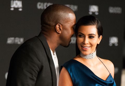 Kanye whispers to Kim on a red carpet in November 2014.