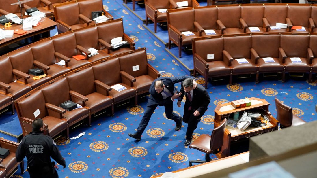 Members of Congress run for cover as rioters try to enter the House chamber.