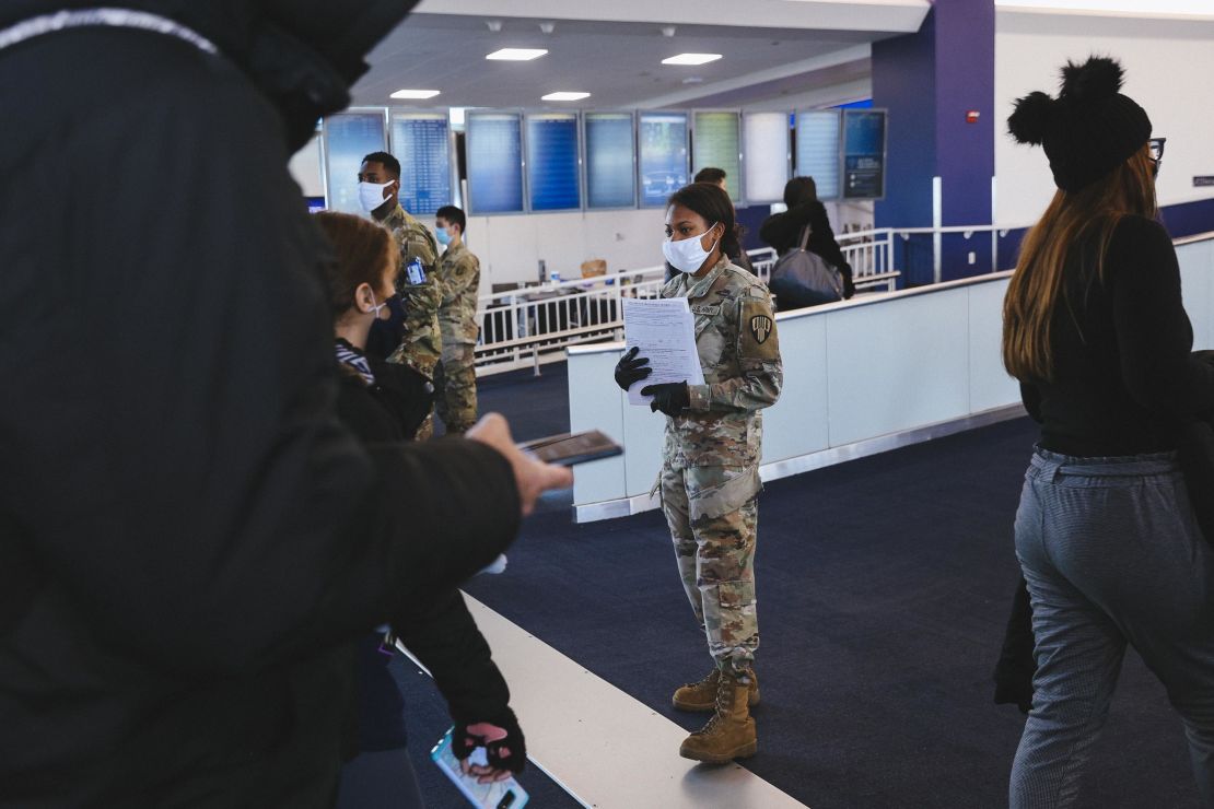 A member of the New York Army National Guard hands out health forms to travelers wearing protective masks at LaGuardia Airport on December 24.