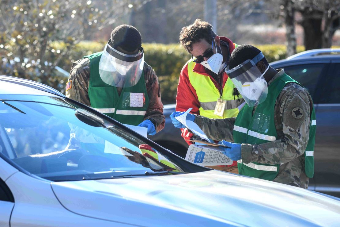 From left, Mississippi National Guard Spc. Timothy Kelly, state health department environmentalist  Anthony Claytor and Spc. Hinton Lindun check paperwork for a patient at the Covid-19 vaccine drive-through clinic in Hattiesburg, Mississippi, on Tuesday.